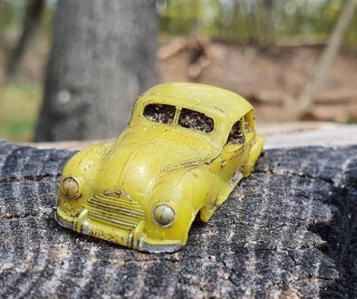 Kleines gelbes Auto auf einem Baumstumpf